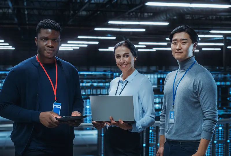 GettyImages-1344731992 Three people in a data center smiling.